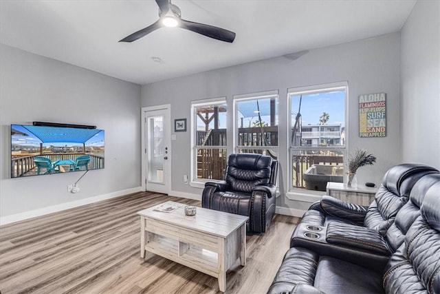 living room with ceiling fan, baseboards, and light wood-style flooring