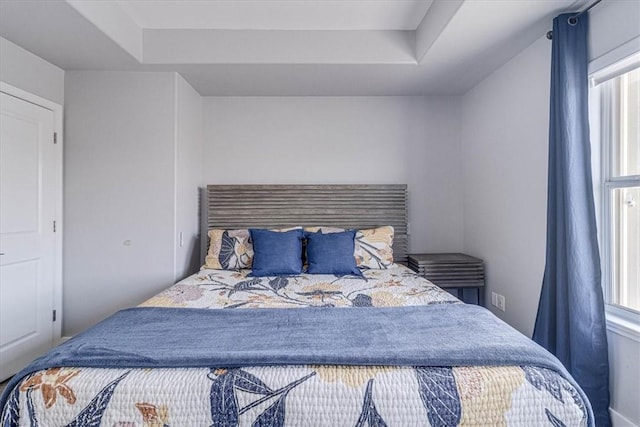 bedroom featuring a tray ceiling and multiple windows