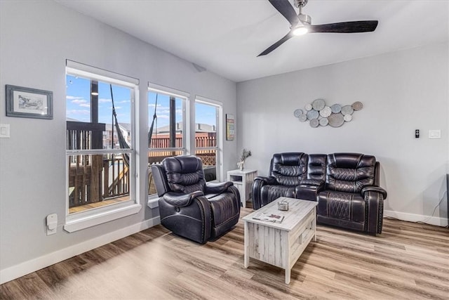 living area with a ceiling fan, light wood-style floors, and baseboards