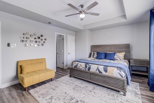 bedroom featuring visible vents, a raised ceiling, and wood finished floors