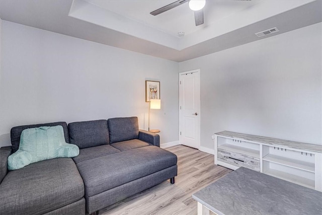 living area featuring visible vents, wood finished floors, baseboards, a raised ceiling, and ceiling fan