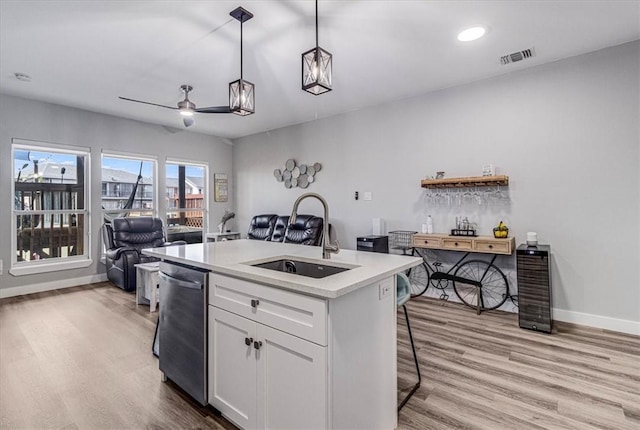 kitchen with a sink, white cabinets, open floor plan, dishwasher, and light wood-type flooring