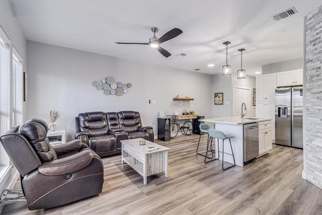 living area featuring light wood finished floors, visible vents, and a ceiling fan