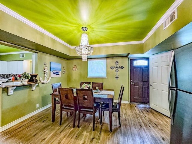 dining space with an inviting chandelier, crown molding, and light hardwood / wood-style flooring