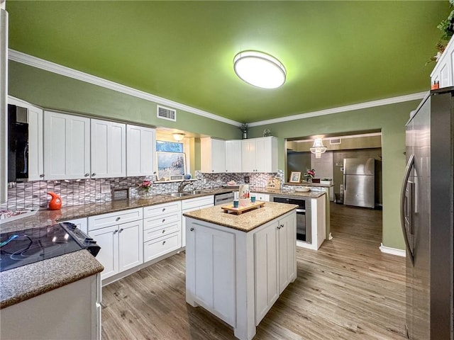 kitchen featuring appliances with stainless steel finishes, a kitchen island, light hardwood / wood-style floors, and white cabinets