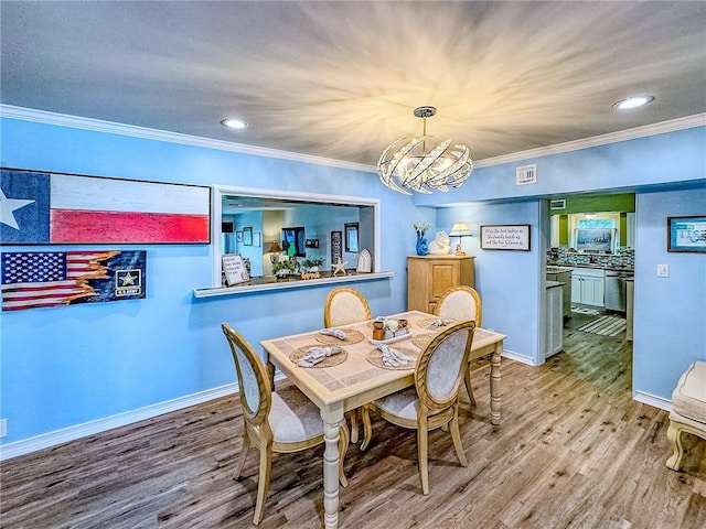 dining room with light hardwood / wood-style flooring, ornamental molding, and an inviting chandelier