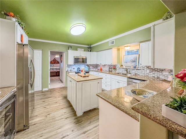 kitchen with stainless steel appliances, sink, white cabinetry, and a center island