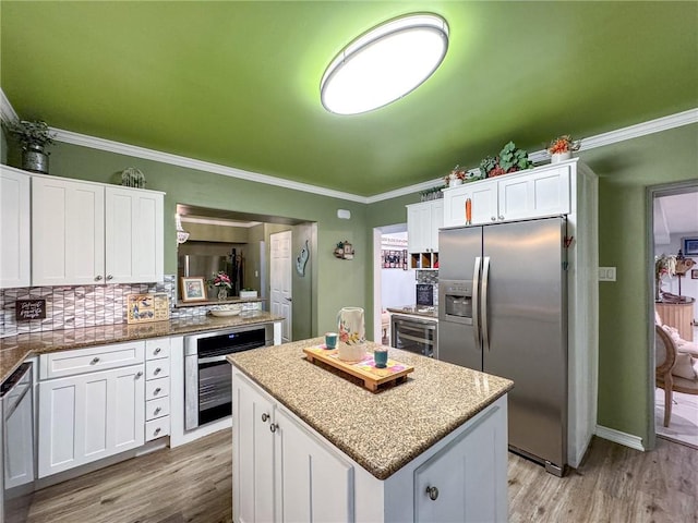 kitchen featuring white cabinets, appliances with stainless steel finishes, a center island, backsplash, and stone counters