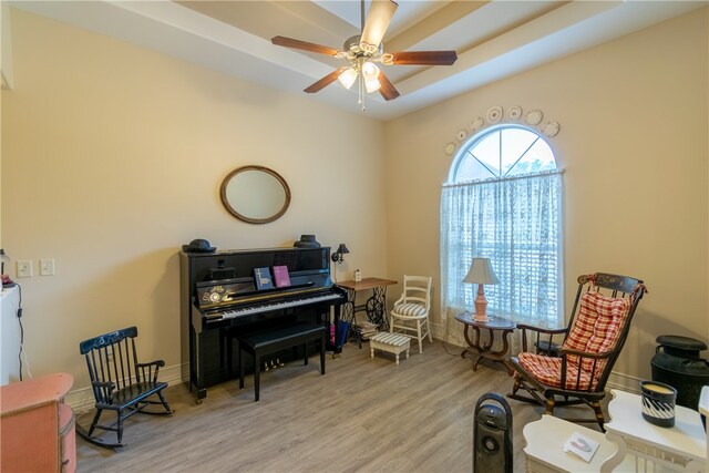 sitting room featuring ceiling fan, a raised ceiling, and light wood-type flooring