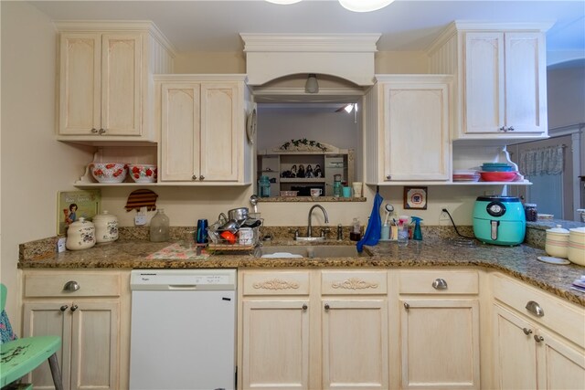 kitchen featuring dishwasher, sink, and dark stone countertops