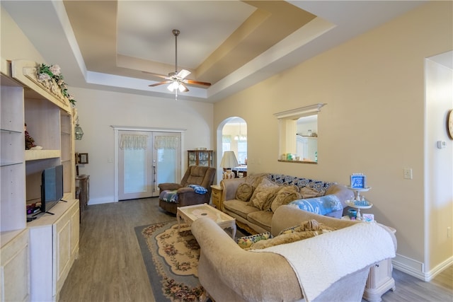 living room featuring light hardwood / wood-style floors, ceiling fan, french doors, and a tray ceiling