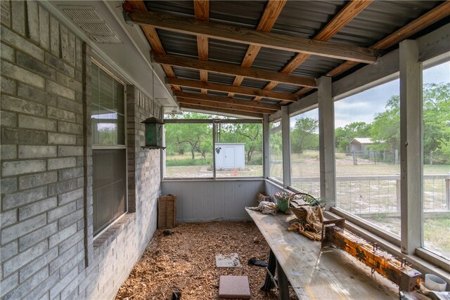 unfurnished sunroom featuring a wealth of natural light and vaulted ceiling with beams