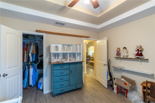 interior space with a closet, ceiling fan, light hardwood / wood-style floors, and a raised ceiling