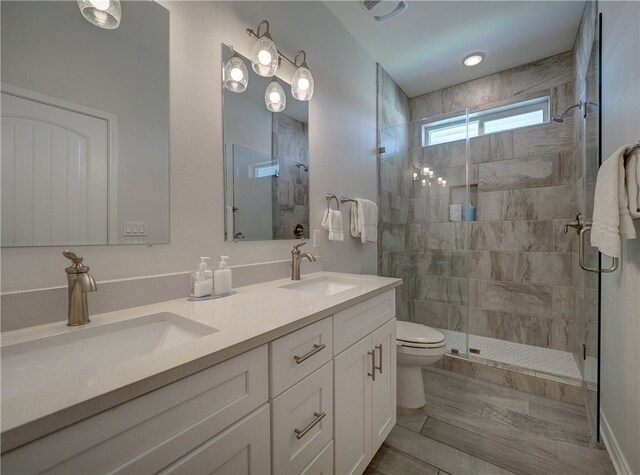 bathroom featuring vanity, a shower with shower door, and toilet