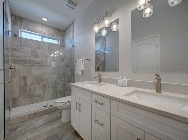 bathroom featuring vanity, a shower with shower door, and toilet