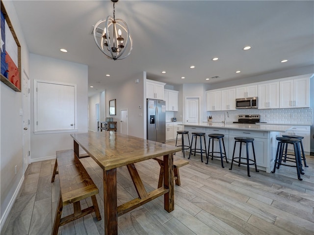 dining area with sink, a notable chandelier, and light wood-type flooring