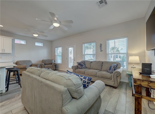 living room with light hardwood / wood-style floors, ceiling fan, and a healthy amount of sunlight