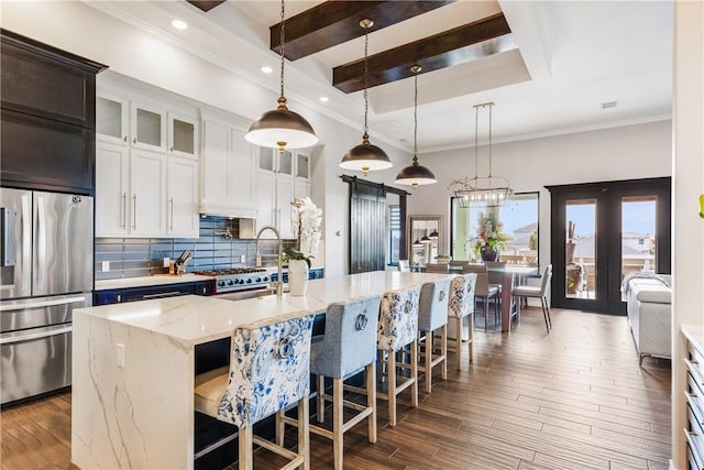 15342 Cartagena Ct, Corpus Christi, TX 78418 - kitchen featuring stainless steel fridge with ice dispenser, decorative backsplash, a kitchen breakfast bar, hanging light fixtures, and an island with sink