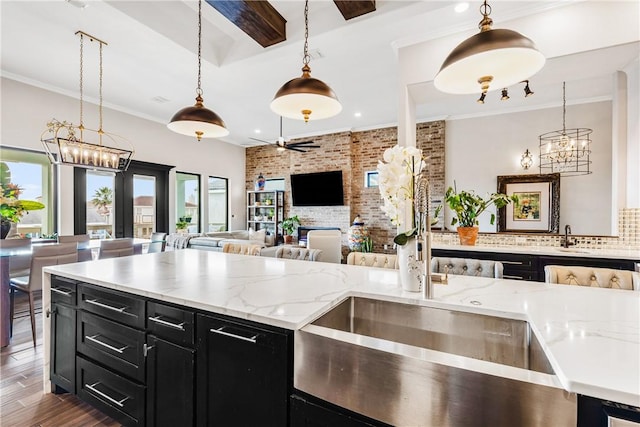 15342 Cartagena Ct, Corpus Christi, TX 78418 - kitchen with dark cabinetry, healthy amount of natural light, a chandelier, brick wall, and a sink