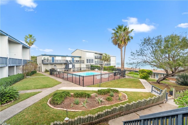 view of community with a swimming pool, fence, and a yard