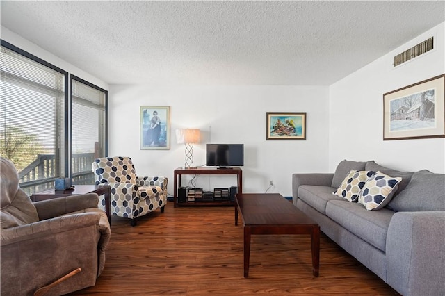 living area featuring dark wood-type flooring, visible vents, and a textured ceiling