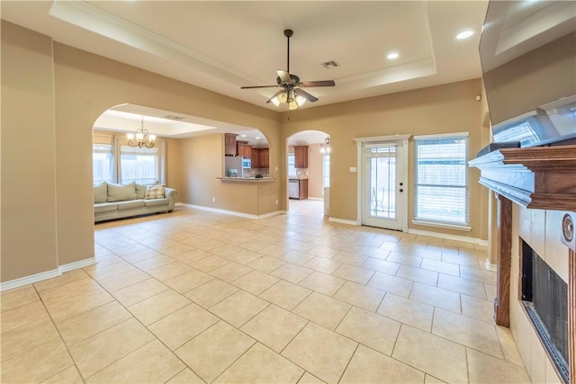 unfurnished living room featuring a raised ceiling, ceiling fan with notable chandelier, and light tile patterned floors