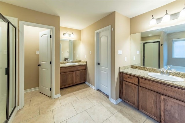 bathroom with a shower with door, vanity, and tile patterned floors