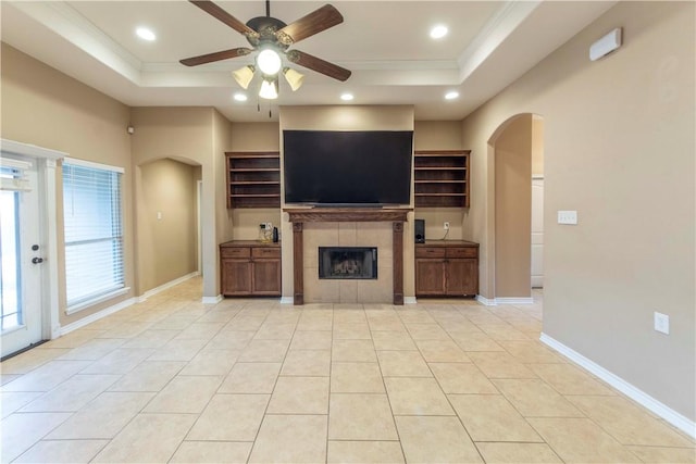 unfurnished living room featuring light tile patterned flooring, ceiling fan, a raised ceiling, and a tile fireplace