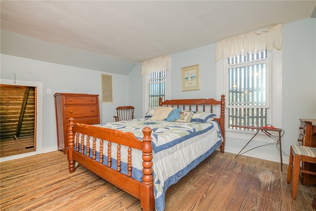 bedroom with multiple windows, wood-type flooring, and a textured ceiling