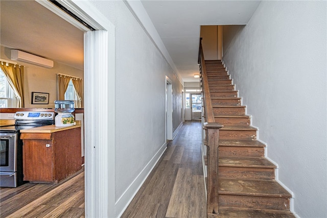 stairway featuring hardwood / wood-style floors, an AC wall unit, and a wealth of natural light