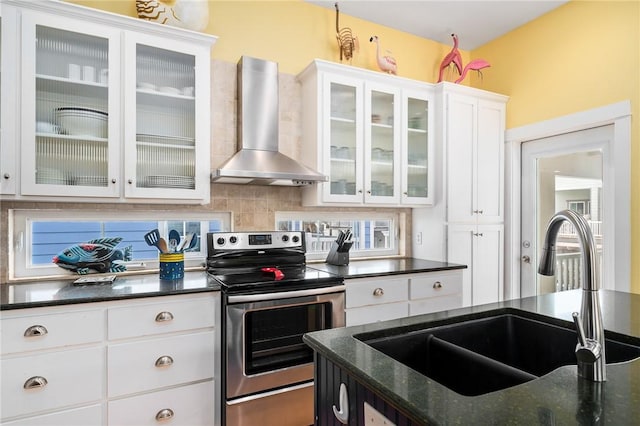 kitchen with sink, wall chimney exhaust hood, electric stove, decorative backsplash, and white cabinets