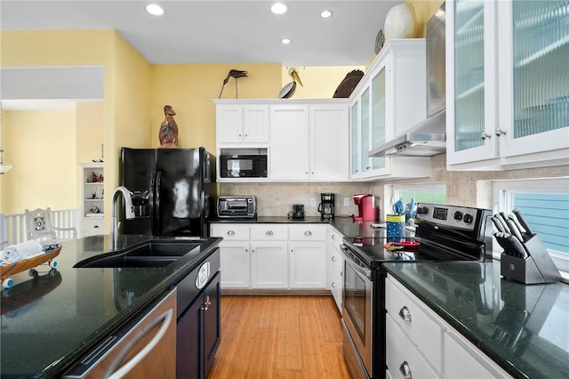 kitchen featuring white cabinetry, sink, wall chimney exhaust hood, and black appliances