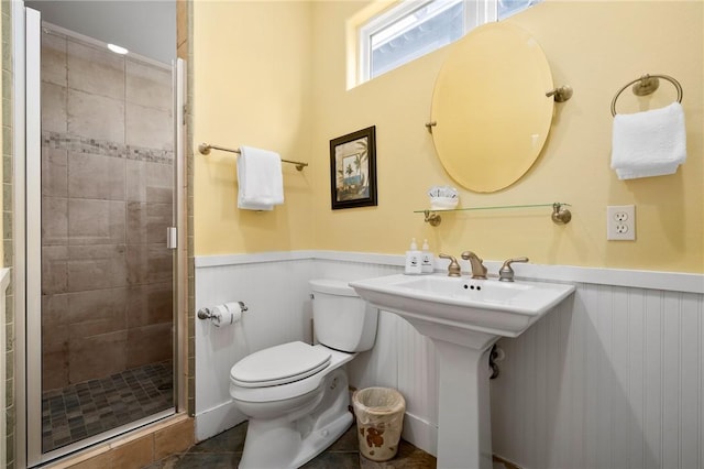 bathroom with tile patterned flooring, toilet, and a shower with shower door