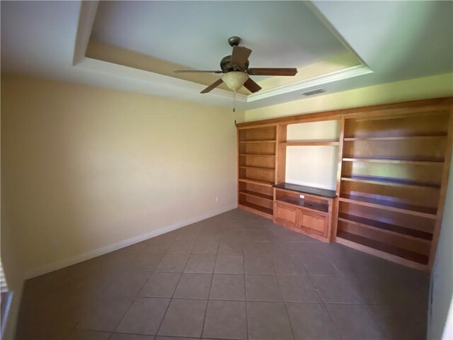 unfurnished bedroom featuring a tray ceiling, dark tile patterned flooring, and ceiling fan