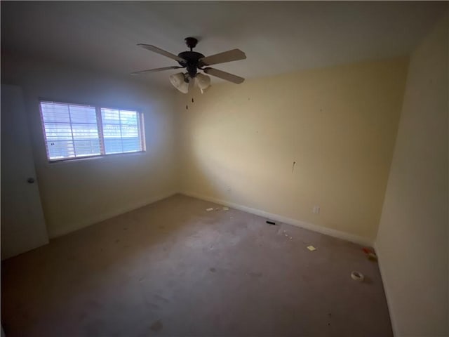 carpeted empty room with a ceiling fan and baseboards