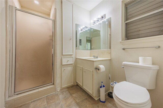 bathroom featuring toilet, vanity, and a shower with door