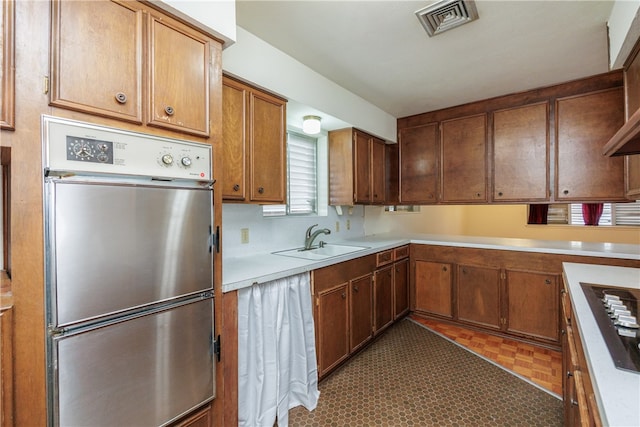 kitchen with black stovetop, sink, light parquet flooring, and oven