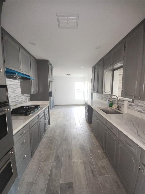 615 E Henderson St, Bishop, TX 78343 - kitchen with visible vents, appliances with stainless steel finishes, dark wood finished floors, a sink, and under cabinet range hood