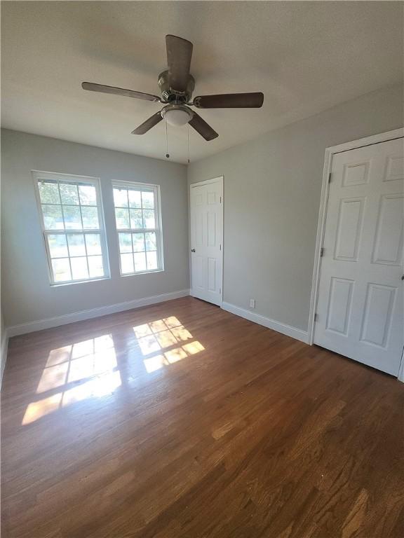615 E Henderson St, Bishop, TX 78343 - unfurnished bedroom featuring baseboards, a ceiling fan, and dark wood-style floors