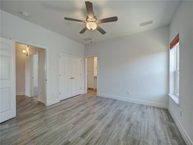 unfurnished bedroom featuring light wood-type flooring, multiple windows, and baseboards