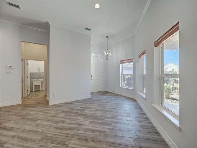 empty room featuring ornamental molding, a chandelier, light wood-style flooring, baseboards, and recessed lighting