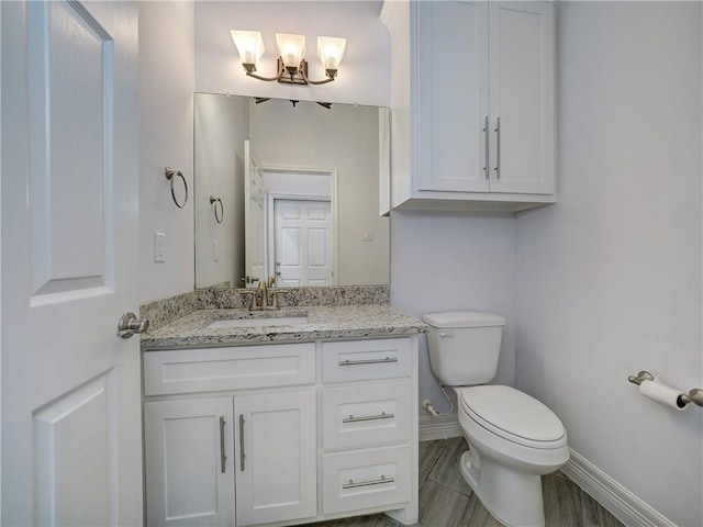 bathroom with baseboards, toilet, a chandelier, and vanity