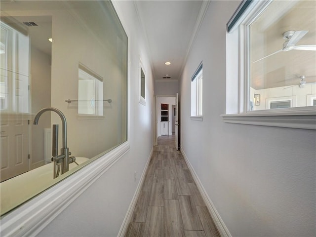 hallway featuring wood finished floors, ornamental molding, and baseboards