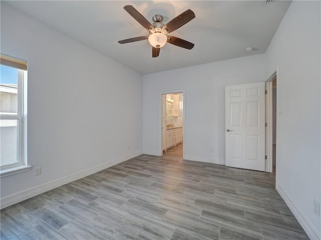 unfurnished bedroom with baseboards, ensuite bathroom, ceiling fan, and light wood finished floors