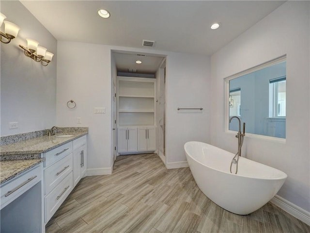 full bath featuring baseboards, recessed lighting, a soaking tub, wood finished floors, and vanity