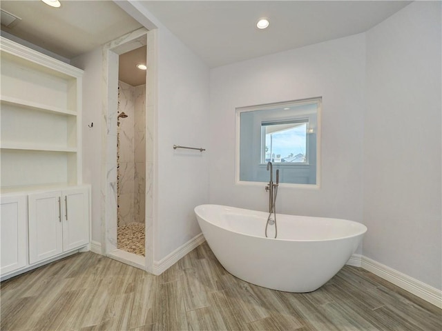full bath featuring wood finished floors, baseboards, a shower stall, a soaking tub, and recessed lighting