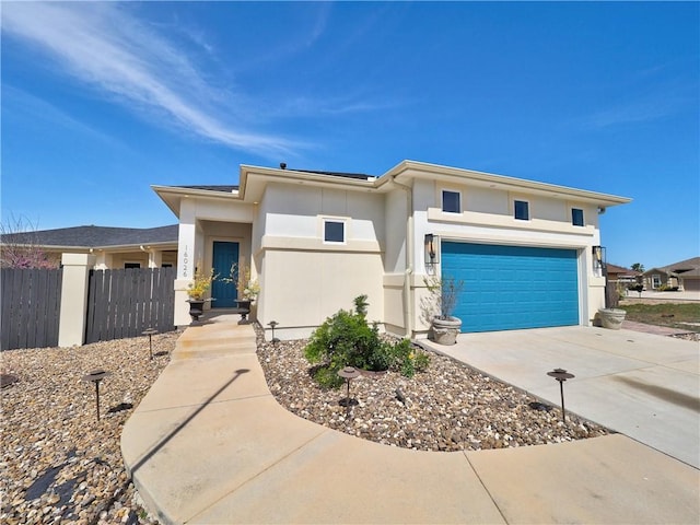 prairie-style home featuring concrete driveway, stucco siding, fence, and an attached garage