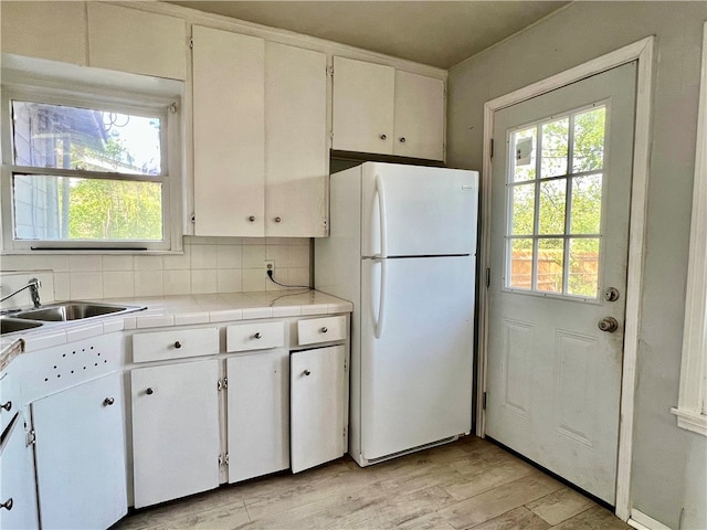 kitchen featuring white cabinetry, white refrigerator, and plenty of natural light