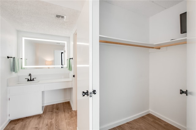 interior space featuring wood-type flooring, a textured ceiling, and vanity