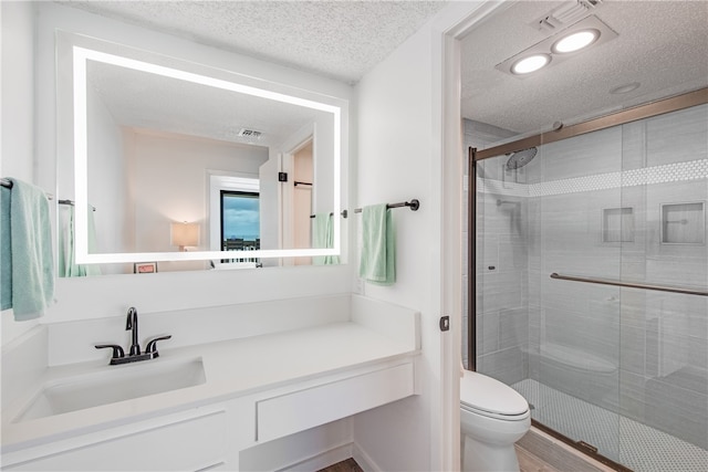 bathroom with wood-type flooring, toilet, a textured ceiling, an enclosed shower, and vanity